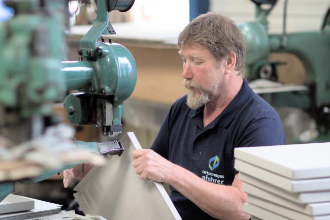 Employé agrafant les angles de couvercles en carton