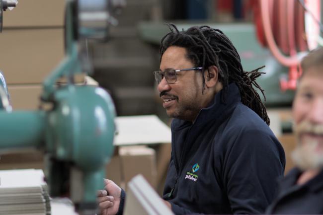 Employé agrafant les angles de couvercles en carton